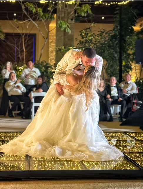 Bride and groom sharing their first dance under string lights at a garden reception.